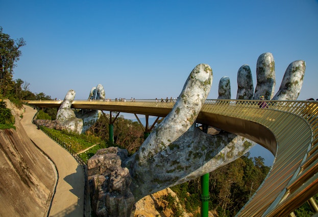 People stroll across the Golden Bridge in Ba Na Hills, which appears to be supported by giant hands