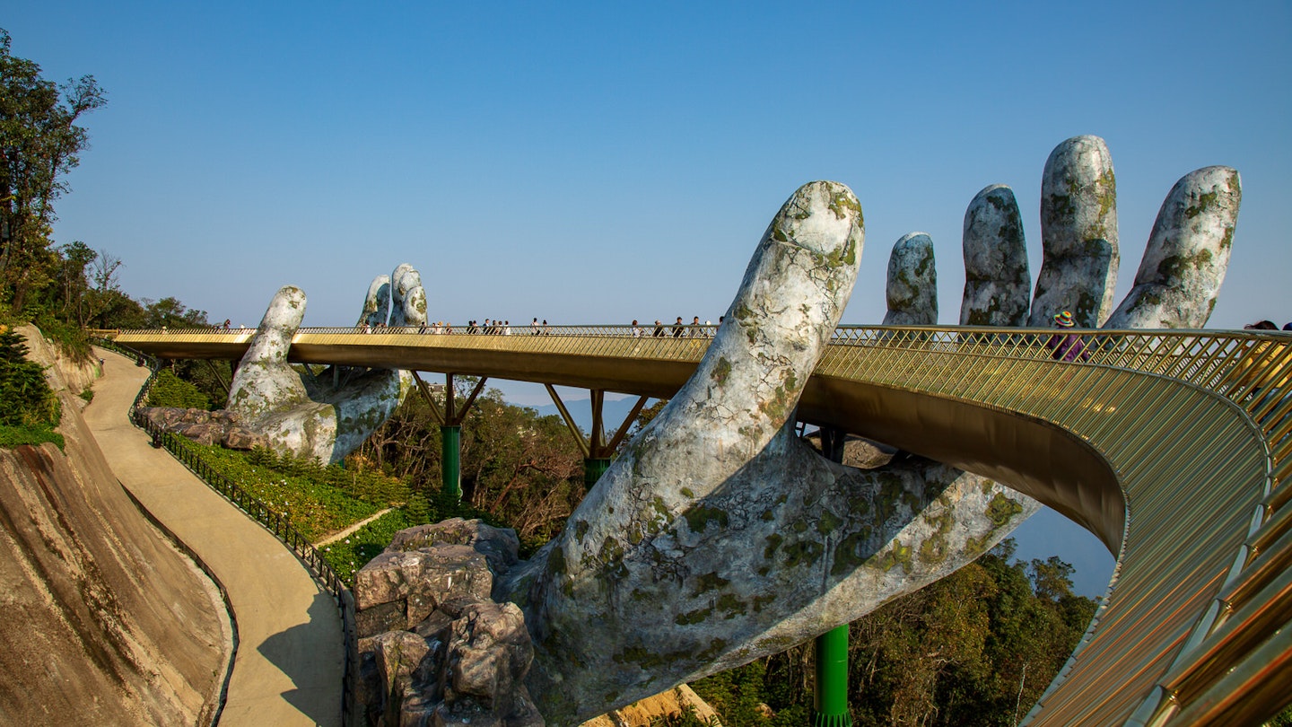 People stroll across the Golden Bridge in Ba Na Hills, which appears to be supported by giant hands