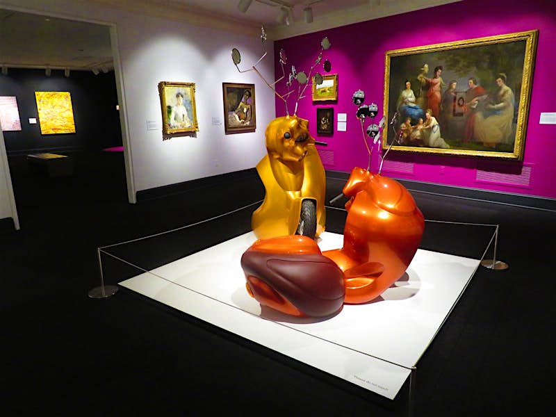 Features - 02.WomeninArts.a-0f68a9144f44 A sculpture that resembles melted vespa scooters is the centerpiece of a colorful gallery in a museum
