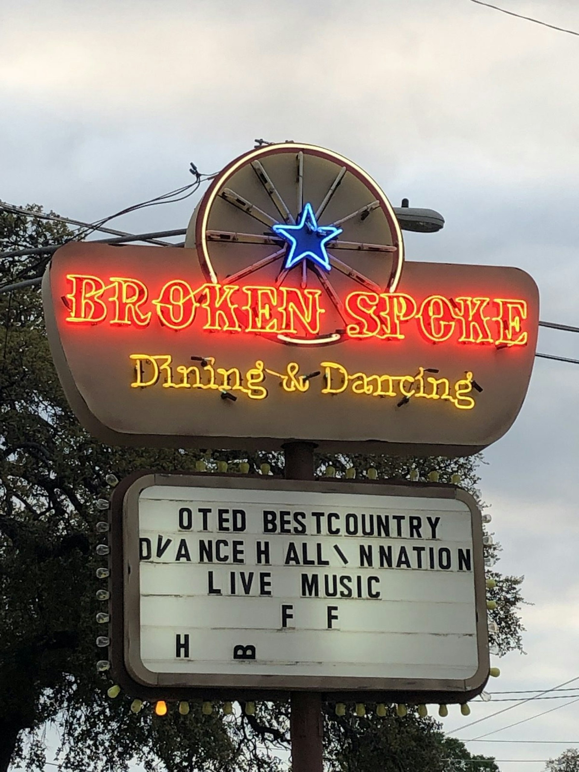 An old-fashioned neon sign and marquee with very crooked letters in the Hill Country says this was voted best country dance hall in the nation
