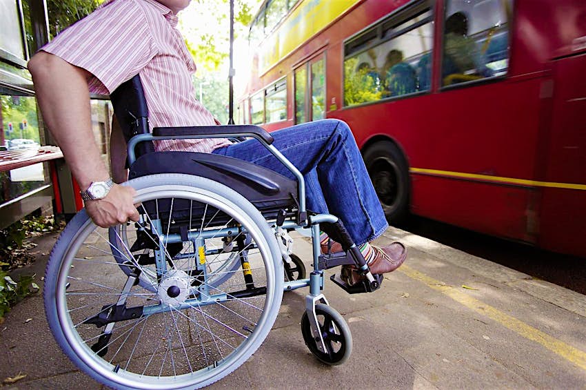 Features - England, London, Disabled man in wheelchair at bus stop A wheelchair user waits for a London bus