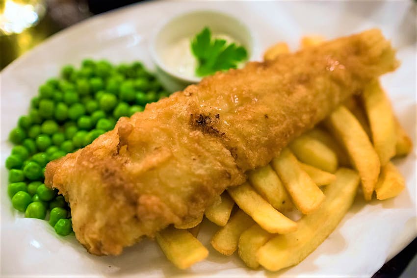 A plate of fish and chips and peas