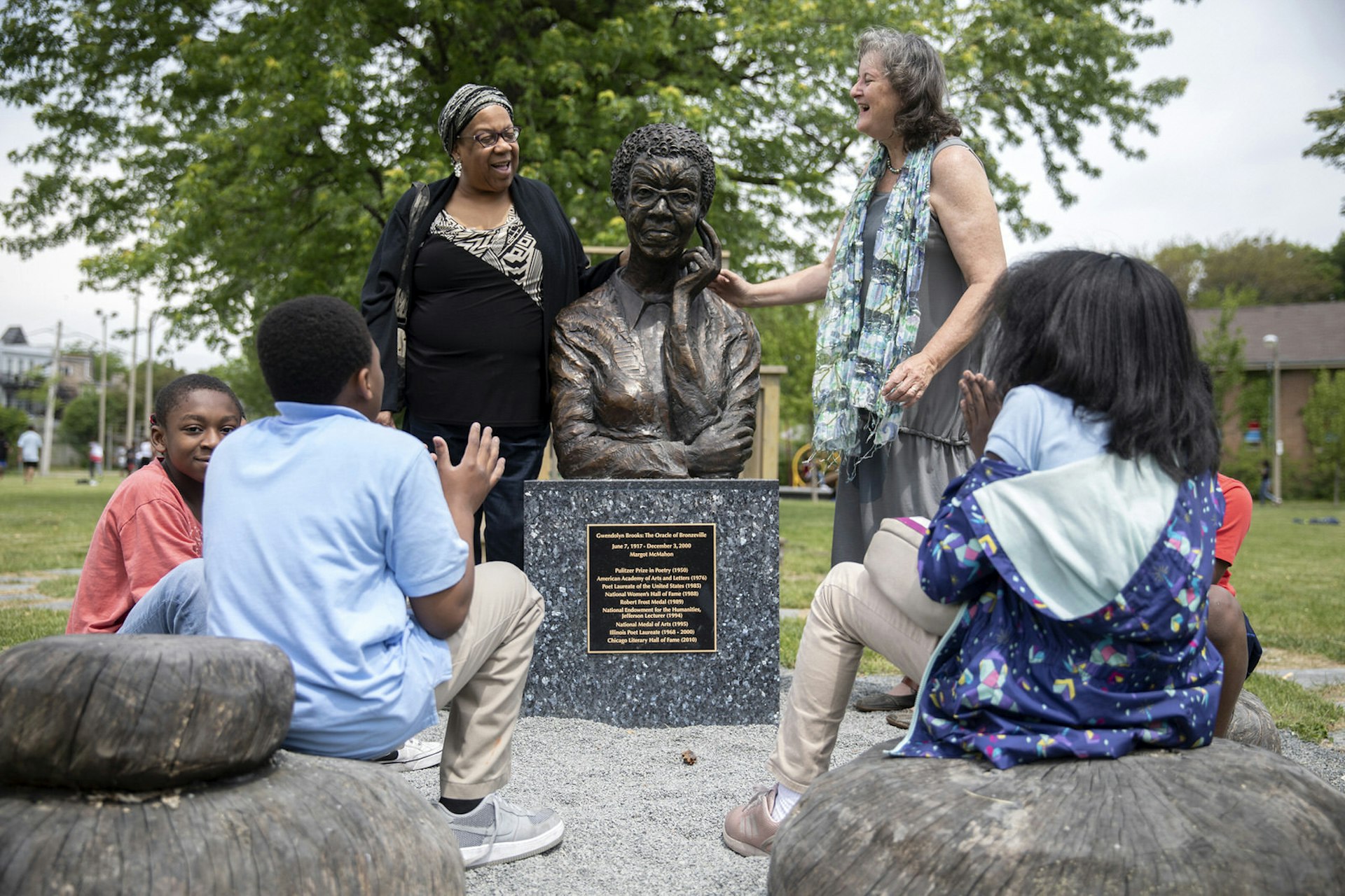 A group of people gather around Gwendolyn Brooks' statue in the Chicago park named after her