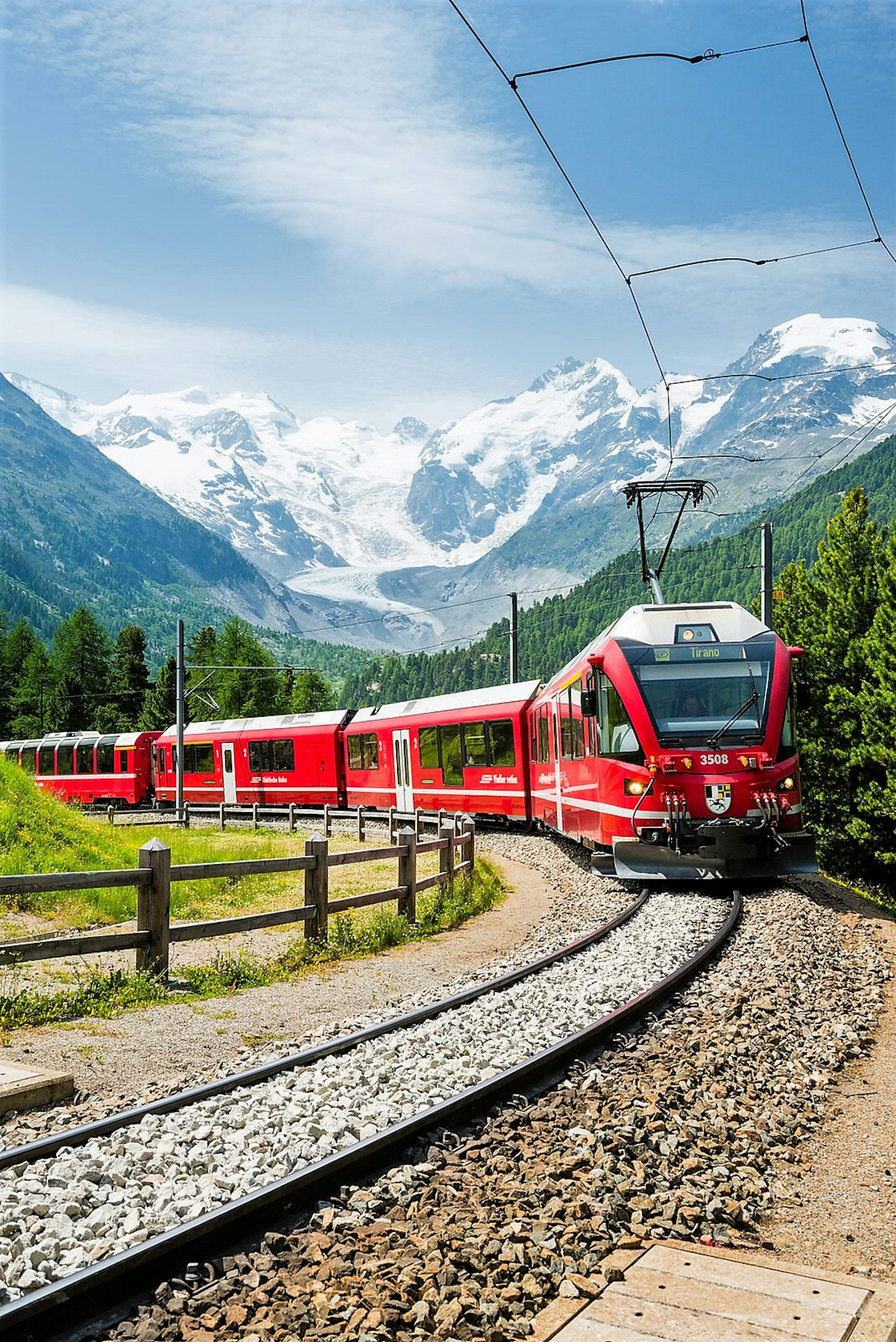 The Bernina Express train follows a curving track with mountains all around it
