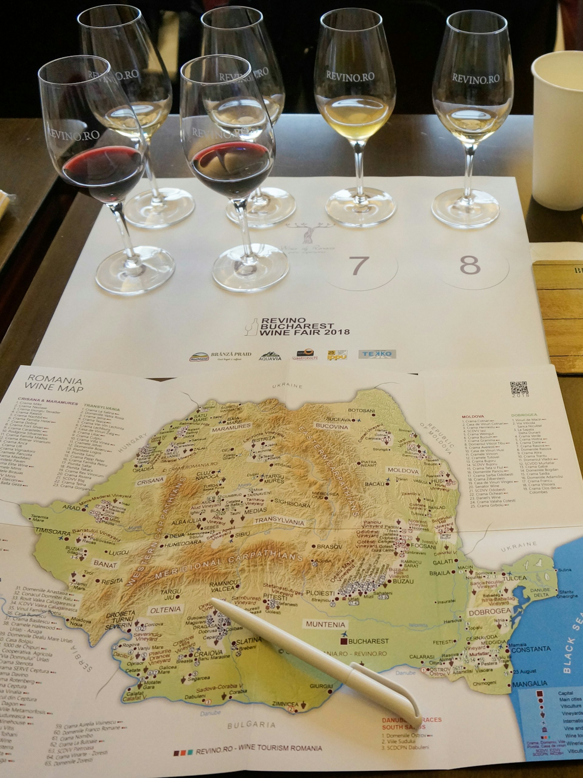 Wine glasses and a map of Romanian wine regions on a table at a wine fair in Bucharest
