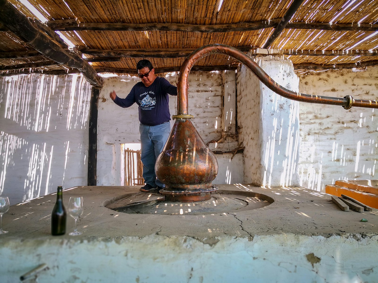 A man walks around a small copper holding tank at a pisco distillery in Peru
