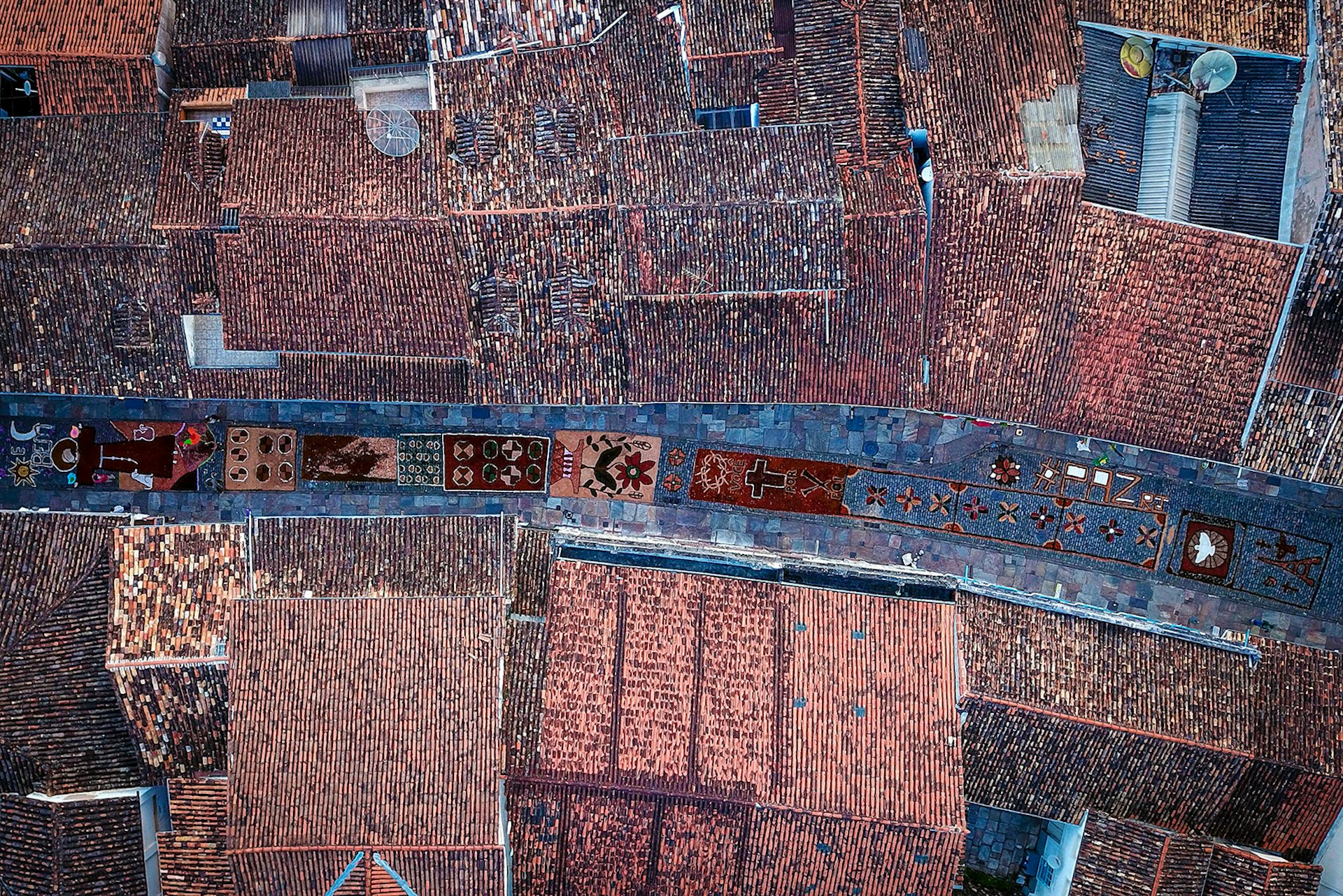 Aerial picture showing sawdust rugs, seen between tiled rooftops, decorating a street in the historic city of Ouro Preto in Brazil during Easter   