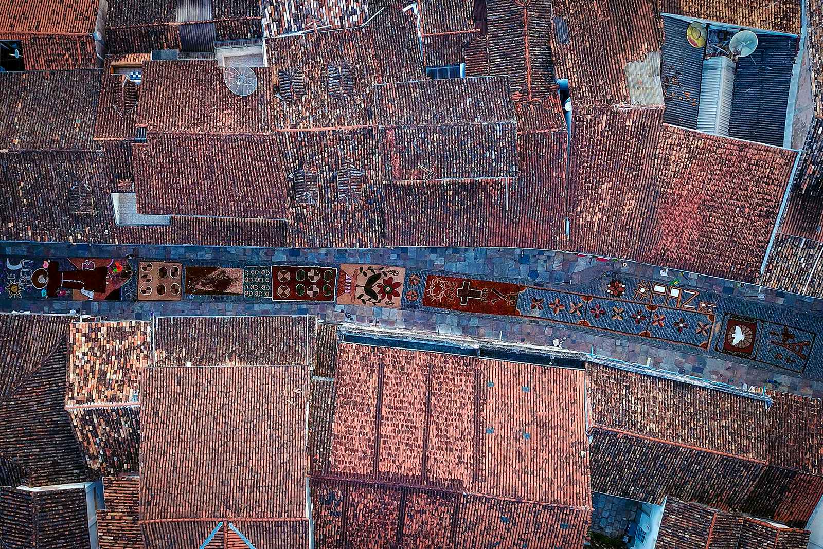 TOPSHOT - Aerial picture showing sawdust rugs, seen between tiled rooftops, decorating a street in the Brazilian historic city of Ouro Preto, Minas Gerais State, on April 1, 2018 before an Easter Sunday procession representing the resurrection of Christ. (Photo by DOUGLAS MAGNO / AFP)        (Photo credit should read DOUGLAS MAGNO/AFP/Getty Images)