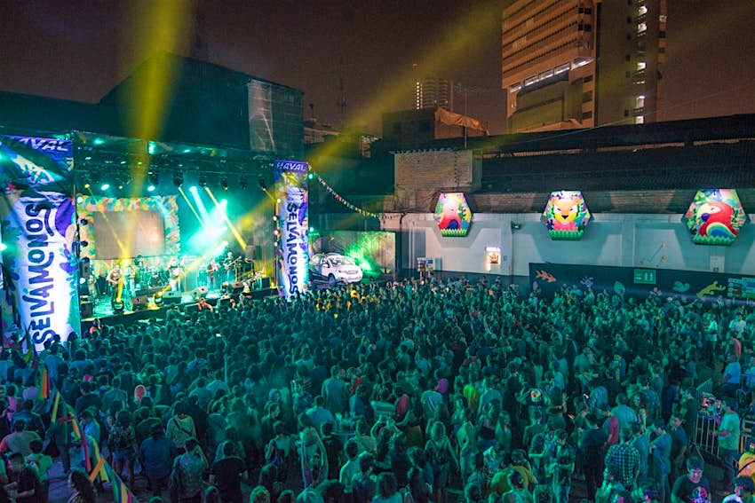 A crowd of people watches a concert on a stage with Selvamonos banners in Lima, Peru