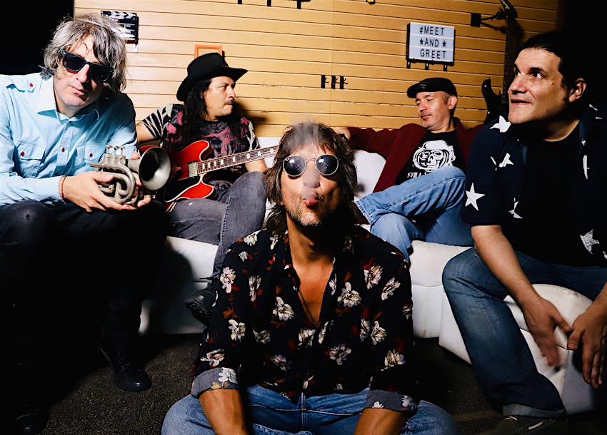 Features - PipeSmokinBand3_Peru-946d94e012ce A band sits on a curved white sofa, with a man sitting in the foreground wearing sunglasses and blowing smoke