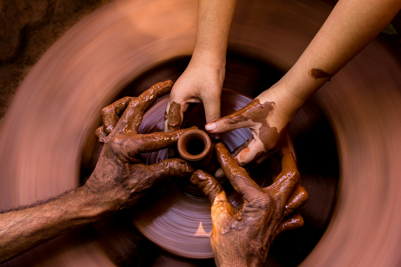 Hands of a potter and student 