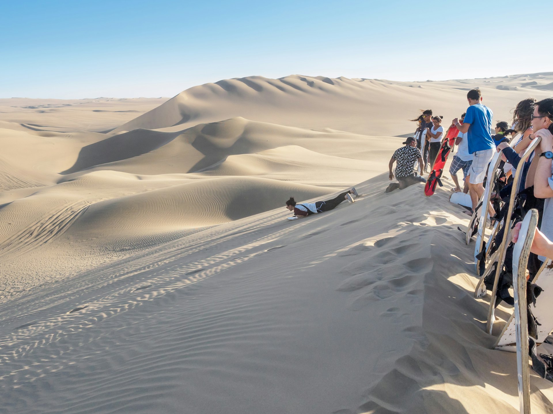 Sandboarding down a dune in Peru