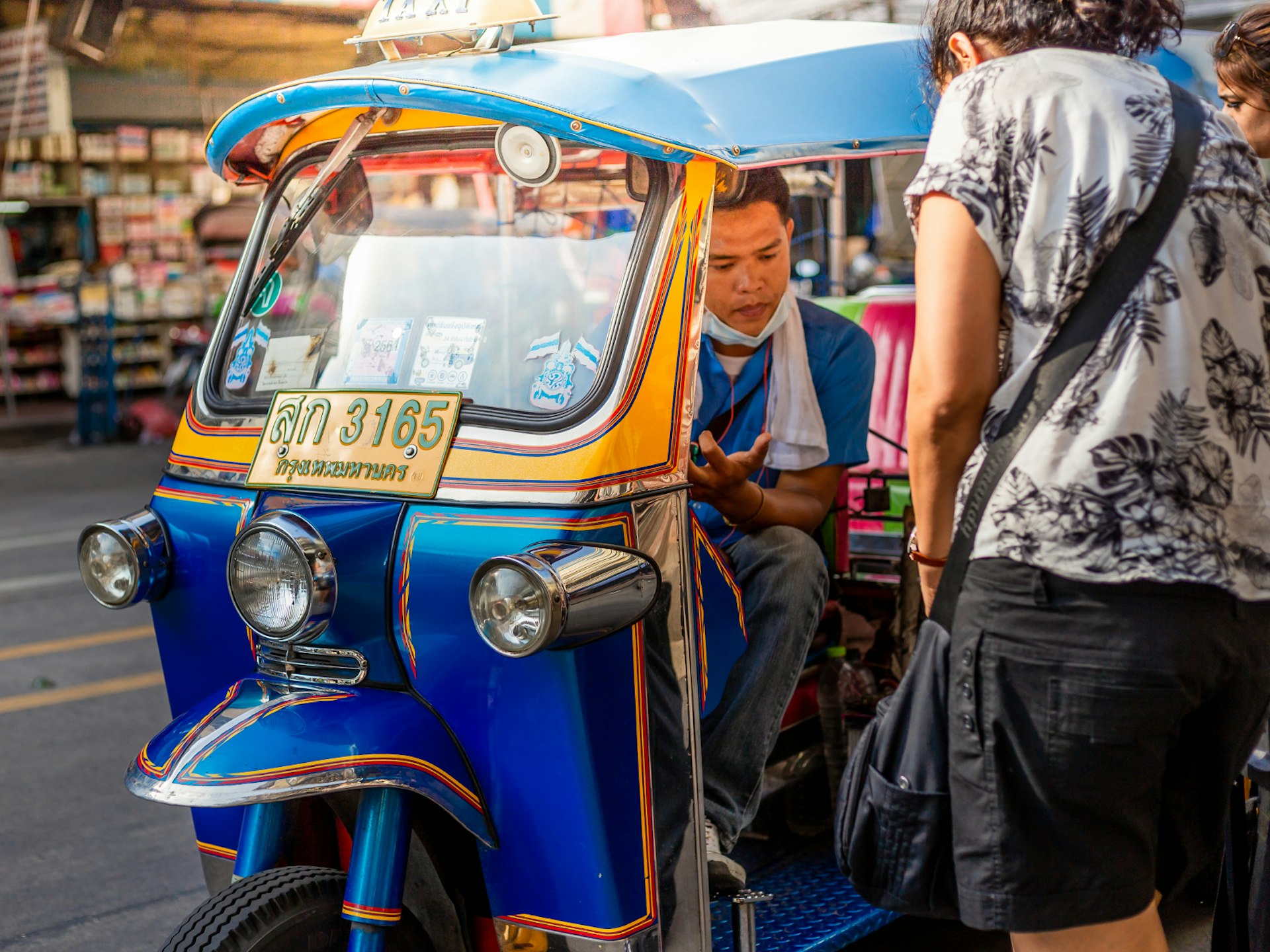 Two people negotiating a tuk tuk fair with the driver in Bangkok