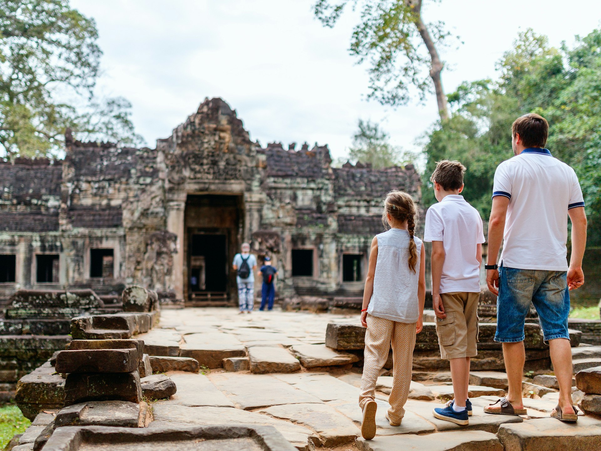 A father and his two children staring at the ruins of Angkor Wat