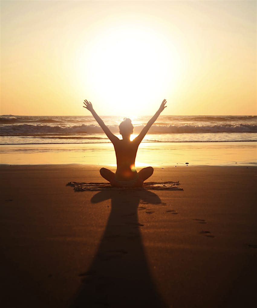Features - Sunset arms raised yoga pose Woman doing yoga on the beach at sunset