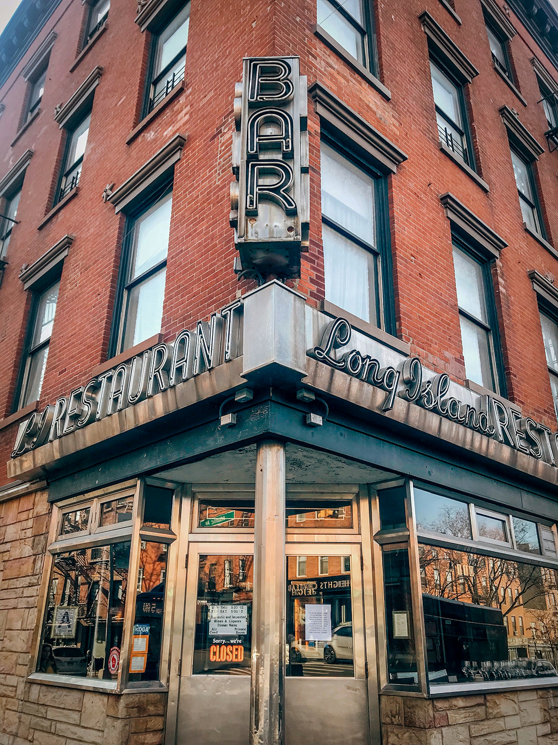 A head-on image of a bar/restaurant on a New York City corner, with signs reading "Bar," "Restaurant," and "Long Island Bar" 