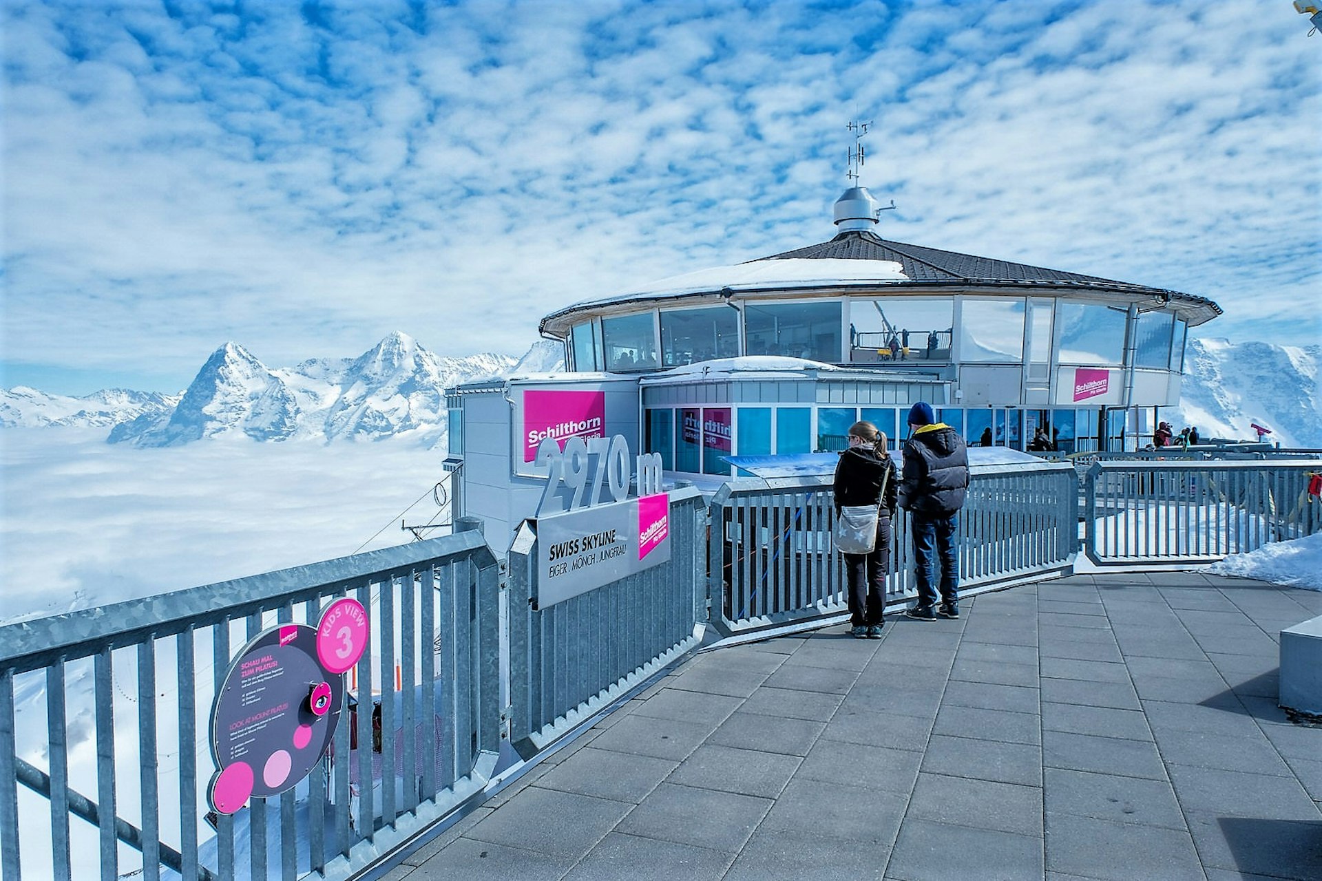 People at the top of the Schilthorn mountain enjoy the view of the surrounding mountains