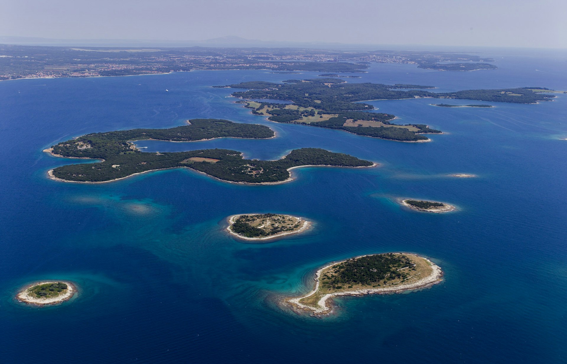 Aerial shot of a dozen small wooded islands, fringed with white beaches