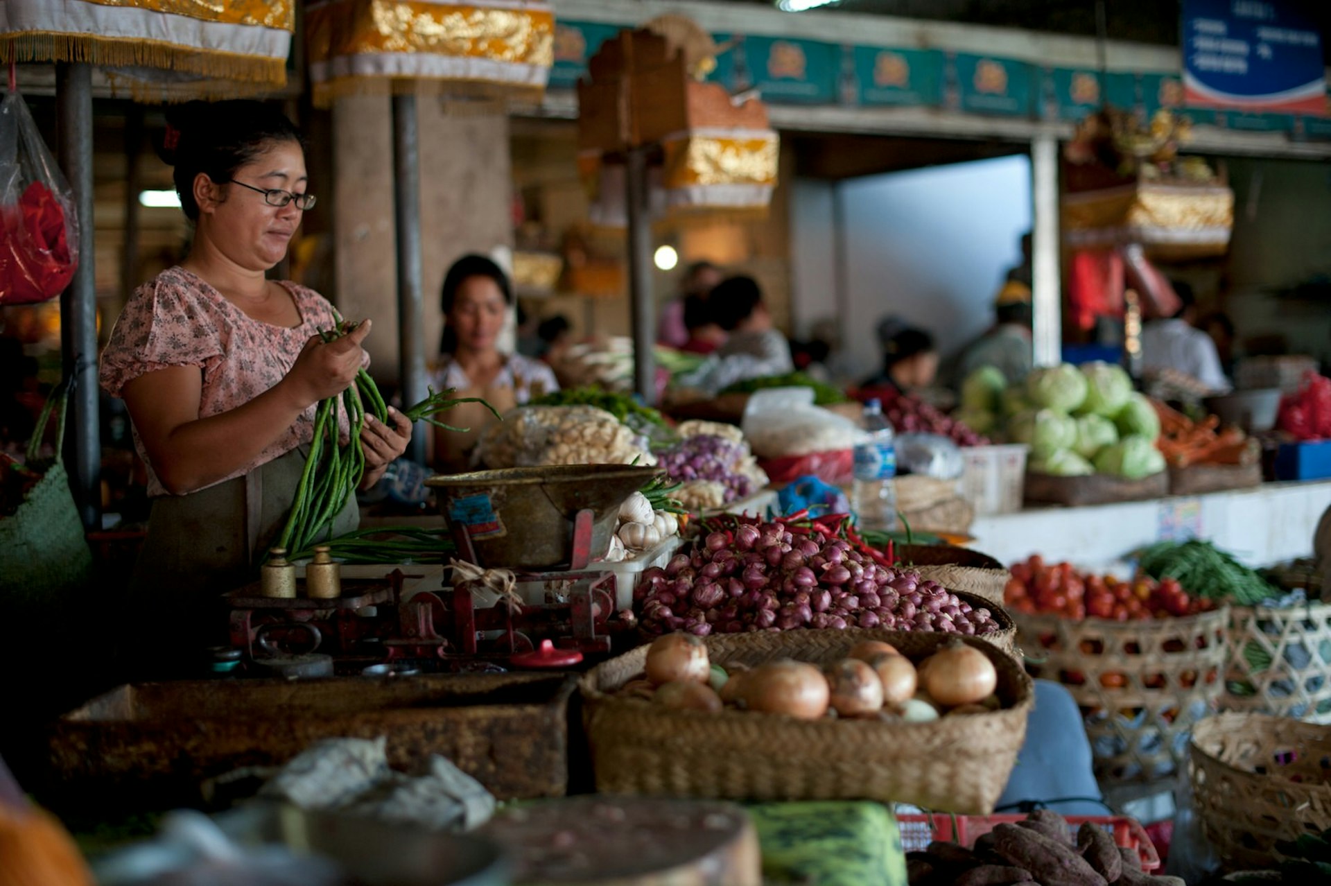 A woman working at a  fresh food market stall in Bali
