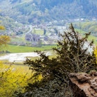 A man stands on a rocky ledge looking down on the ruins of Tintern Abbey