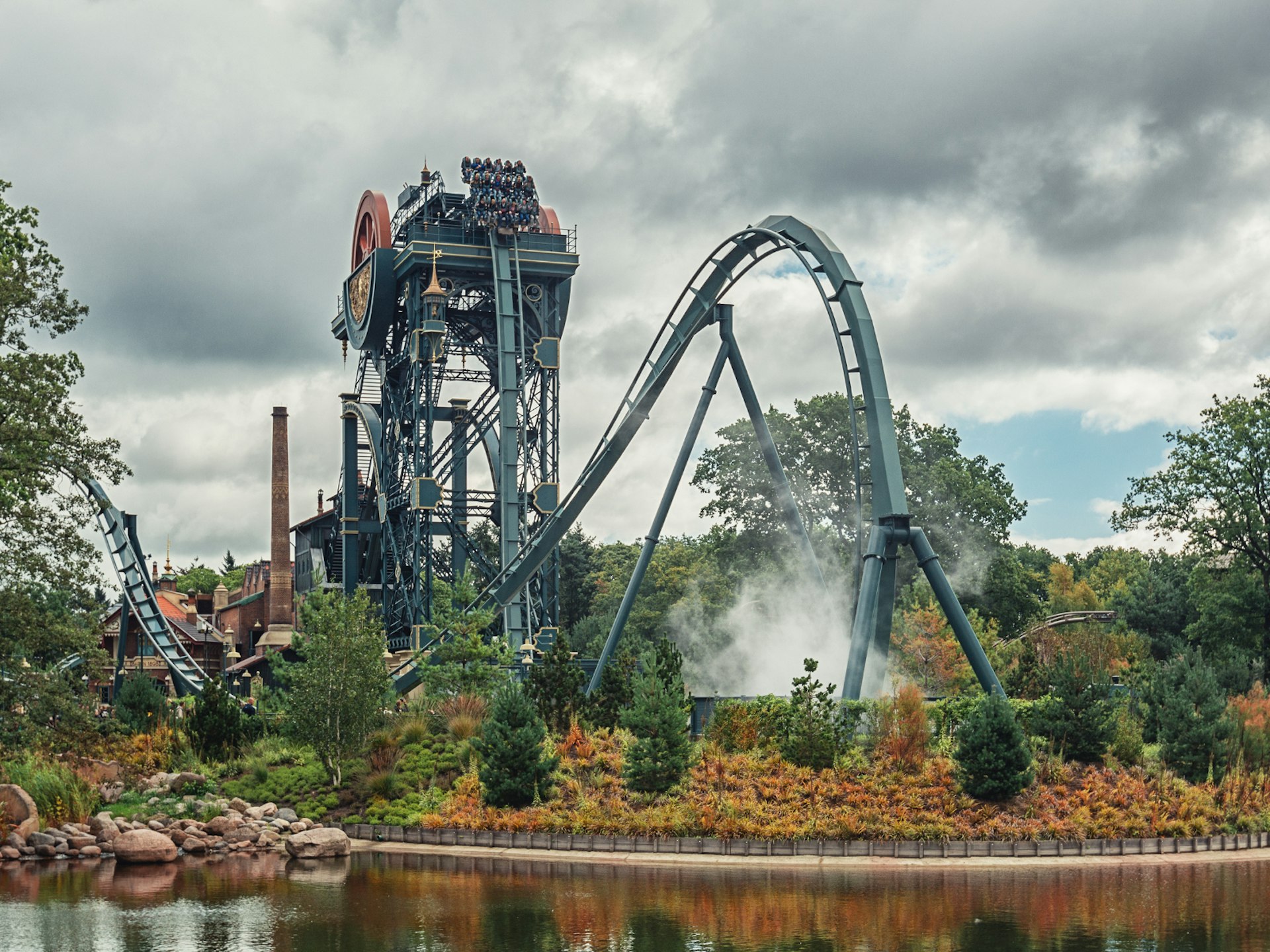 Disney alternatives - The Baron 1898 dive coaster at Efteling theme park, the Netherlands. The huge green-blue metal structure dives below a lake.