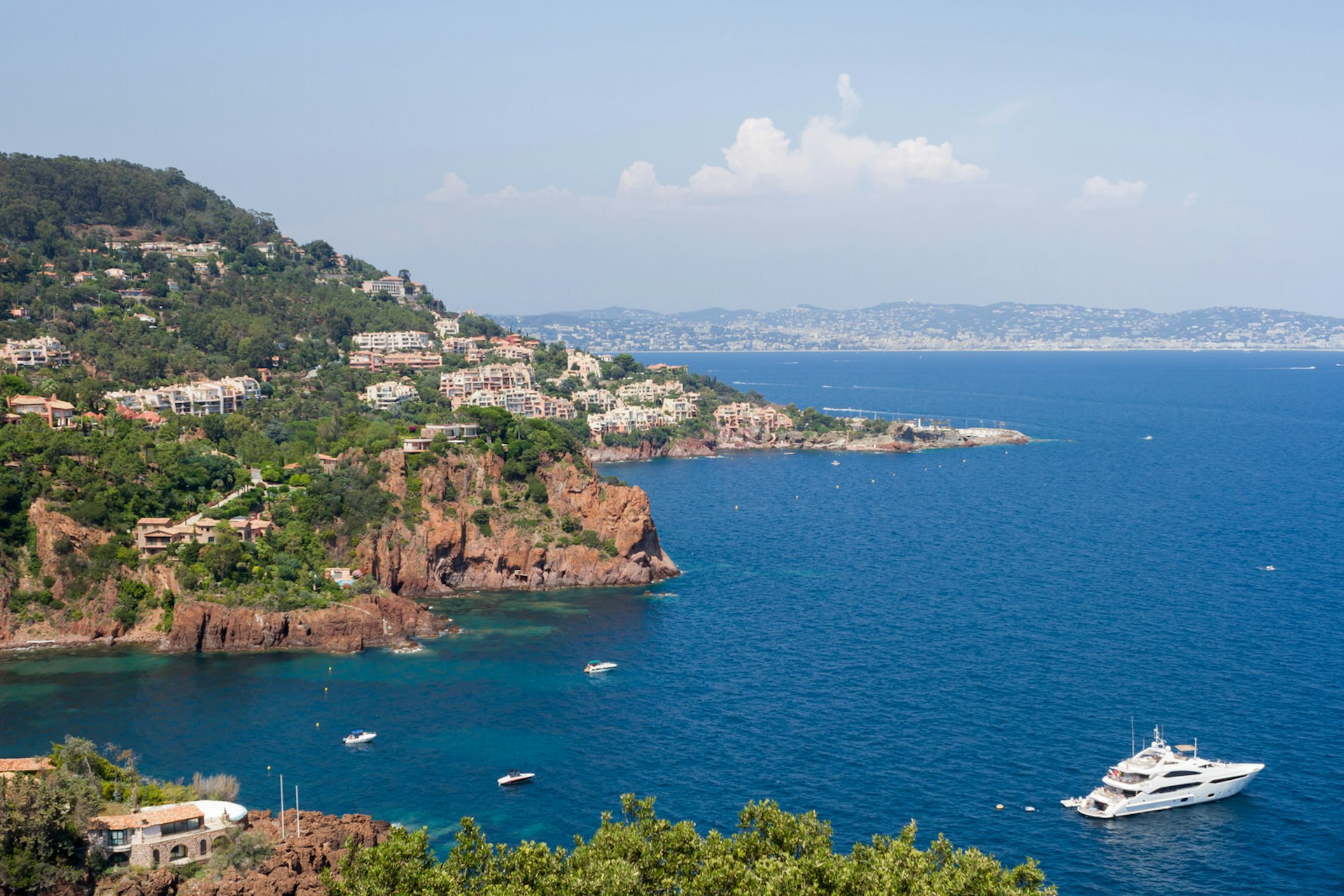 A luxury yacht floats on azure waters along a beautiful bay beach with Cannes in the background ©rochus/Shutterstock