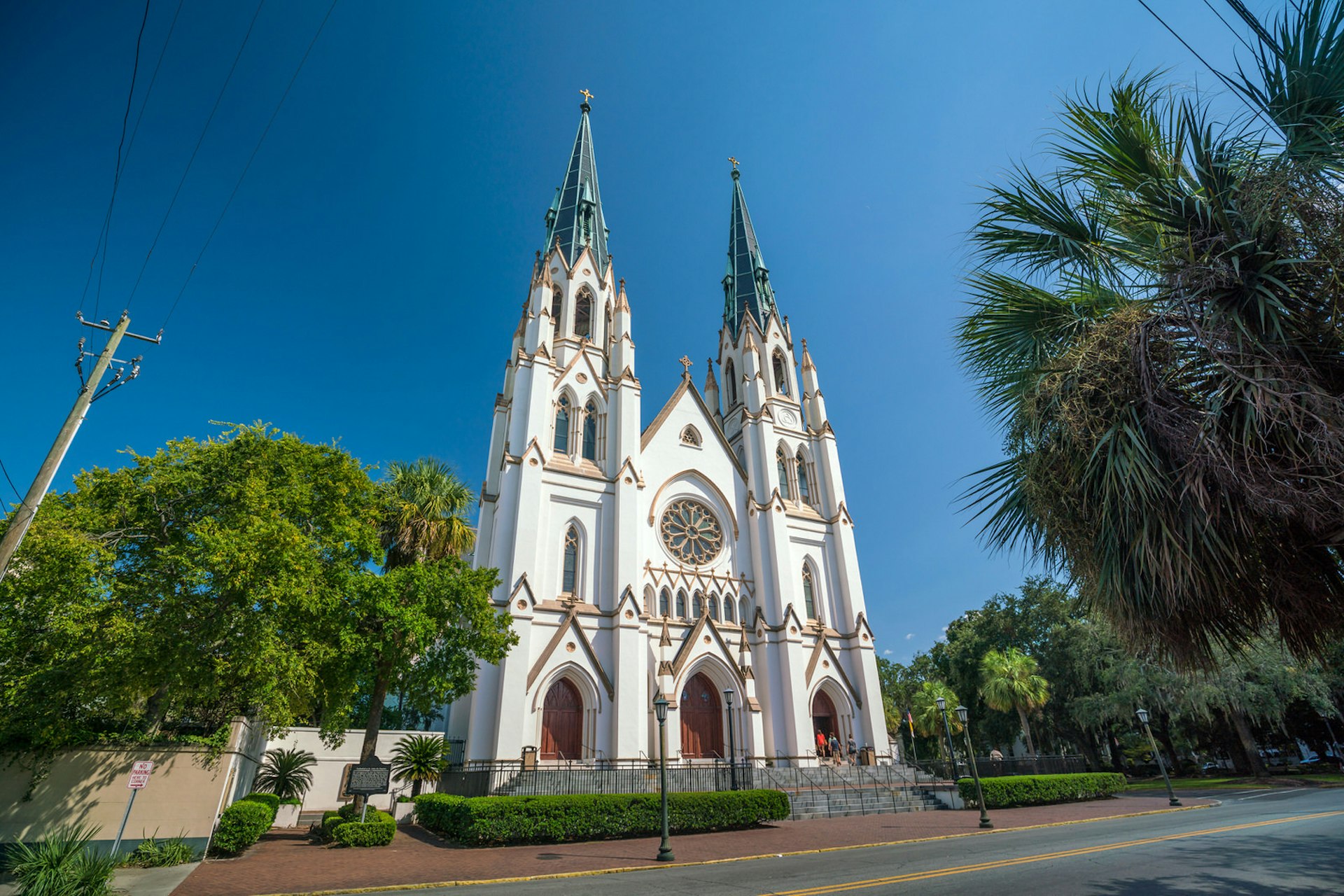 An ornate cathedral under a blue sky and trees surrounding