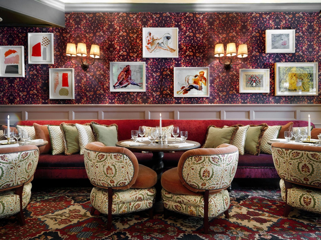 Meghan Markle London - The dining room at Dean Street Townhouse, where Meghan Markle and Prince Harry are said to have had their first date. Image shows a decadent dining room in tones of red and wine with lots of fancy art on the walls as well as plush chairs. © Soho House