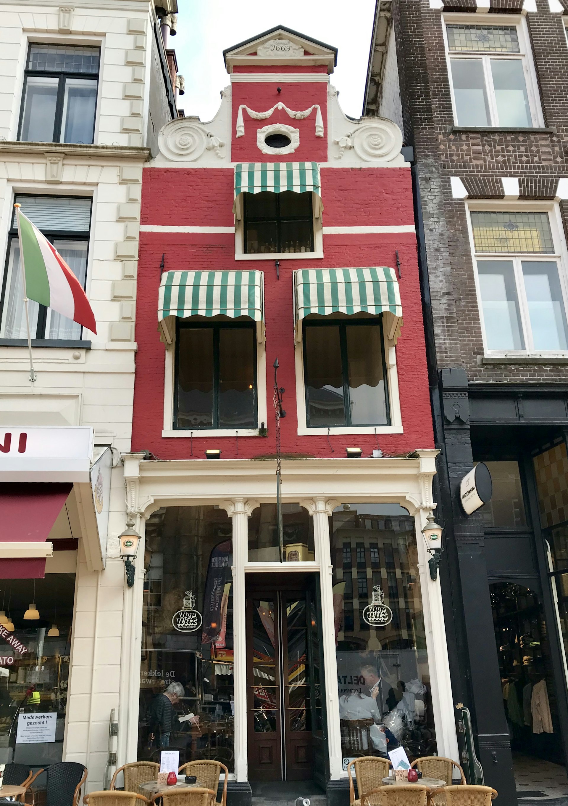 A skinny red building with green and white striped awnings sits sandwiched between two others in Groningen, Netherlands
