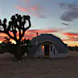 A geo-dome house in a desert next to a Joshua Tree