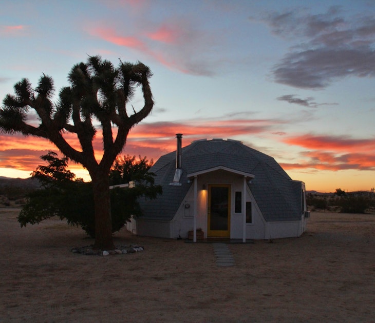 A geo-dome house in a desert next to a Joshua Tree