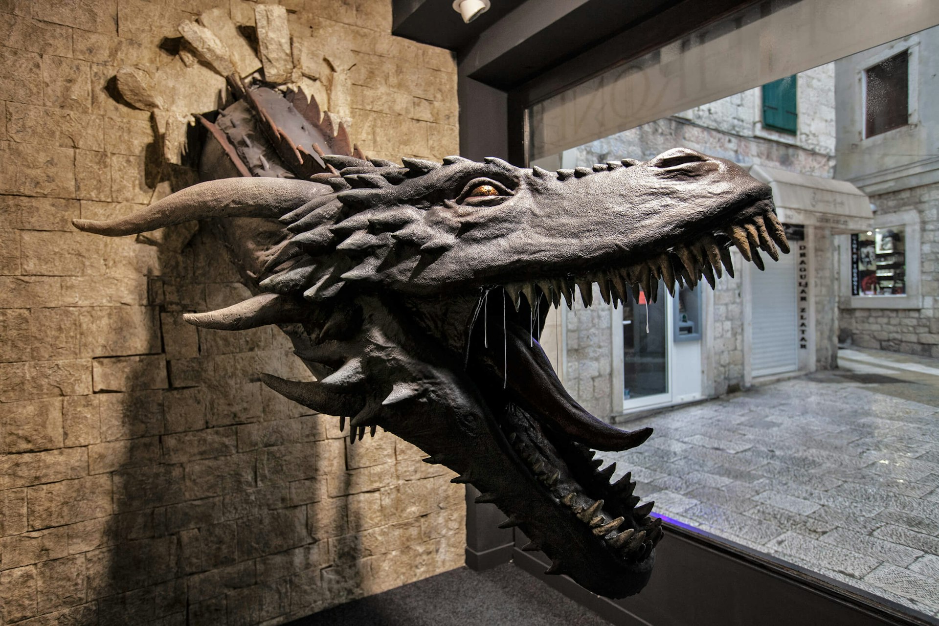 A model of Drogon the dragon bursting through a wall with his jaws open at the Game of Thrones' museum in Split