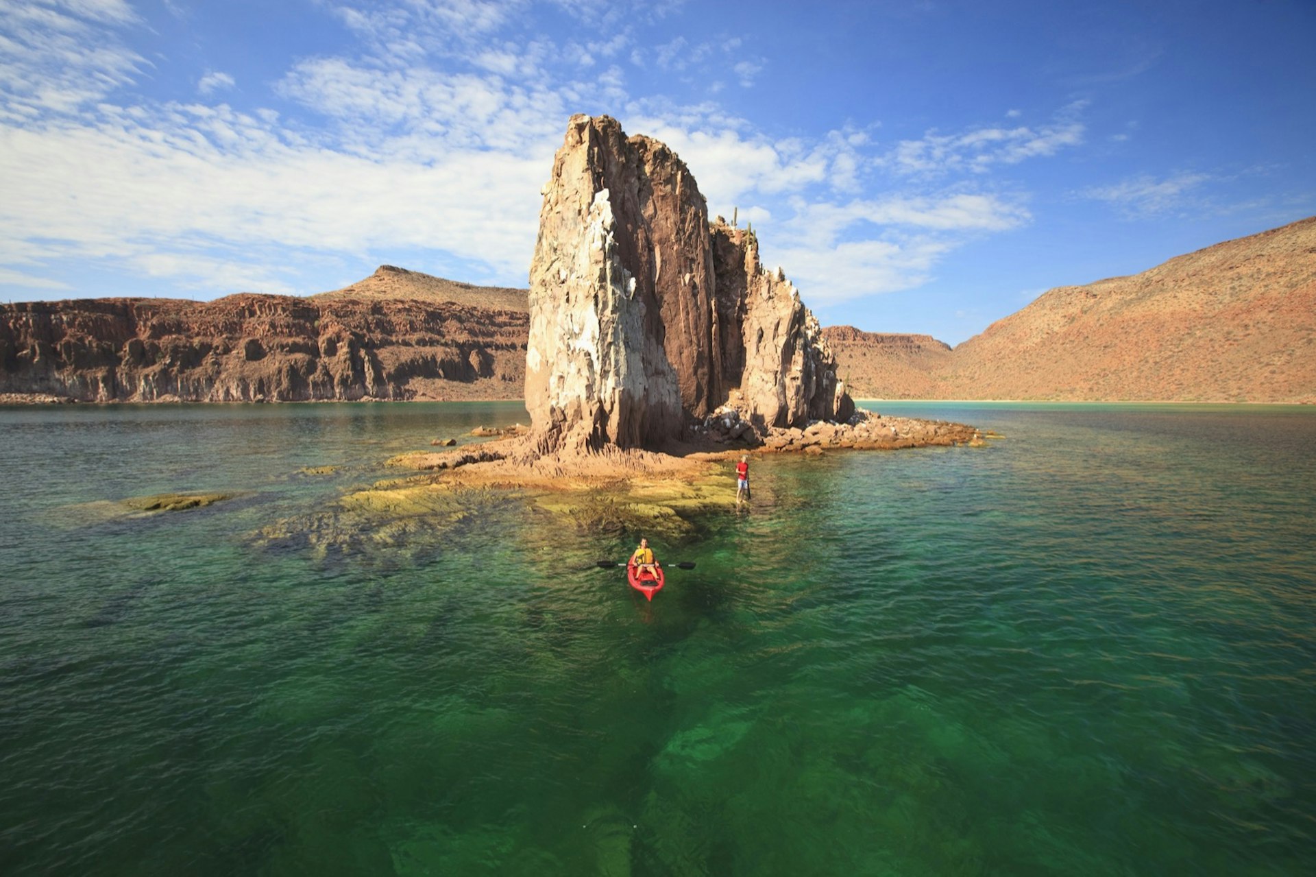 a kayaker paddles past a rocky island