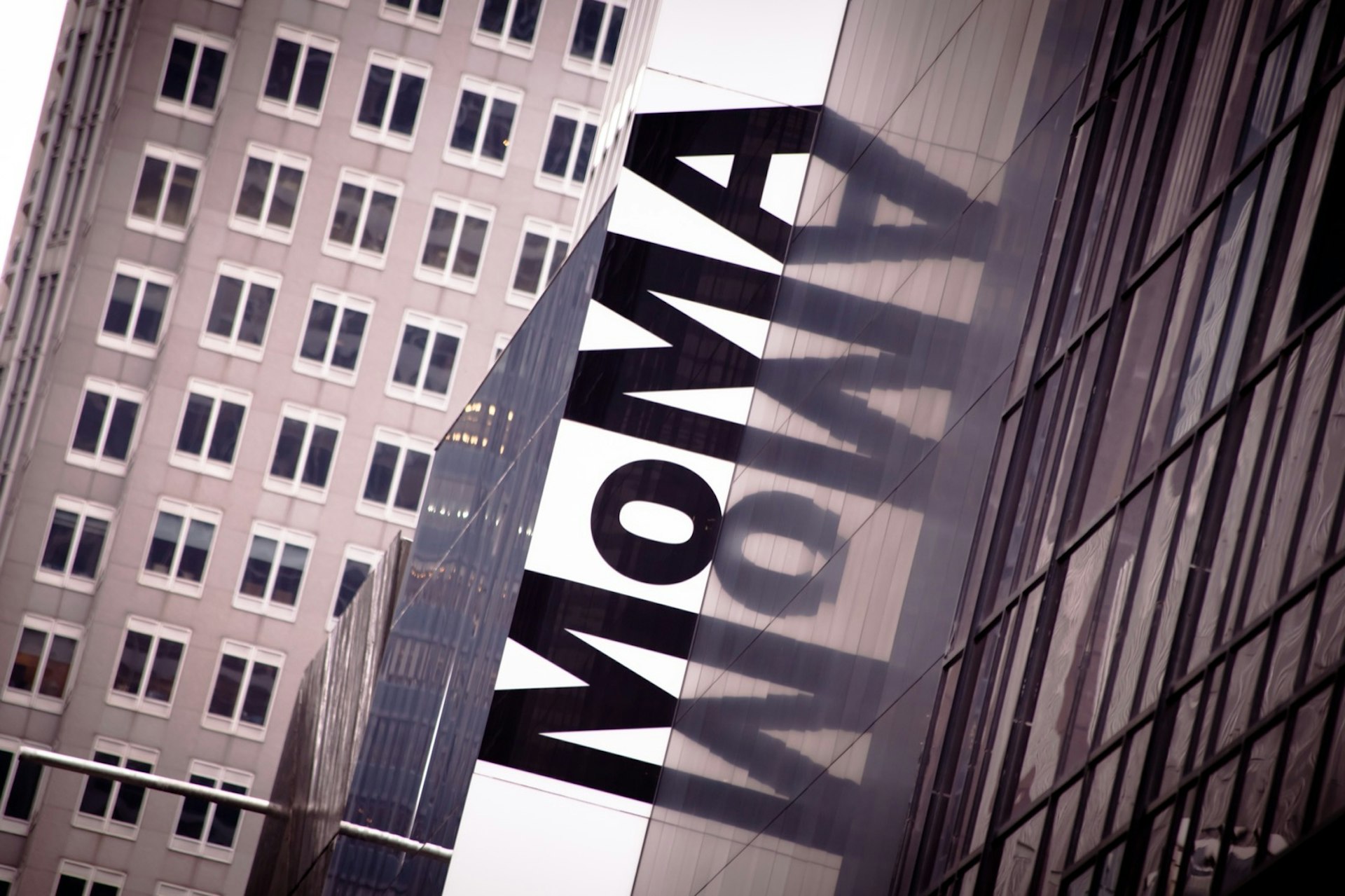The Letters MOMA are reflected in the windows of a museum in New York City