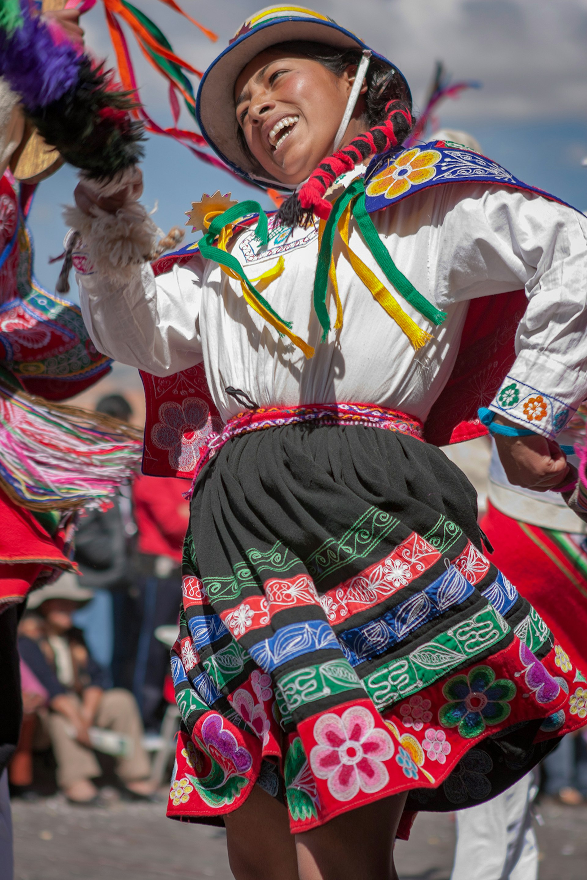 A woman wearing a colorful traditional Inca skirt and a white blouse dances in Plaza de Armas, Cuzco, Peru