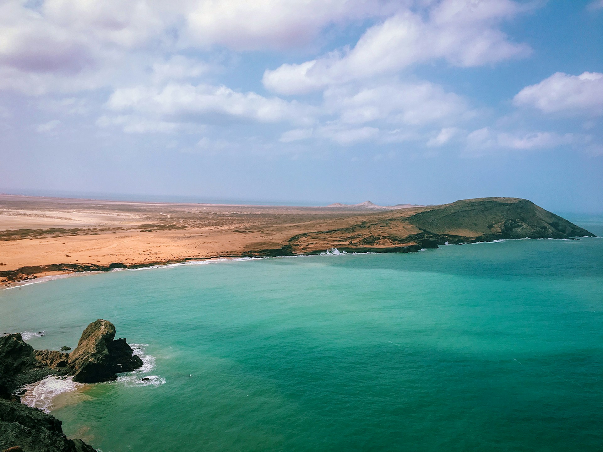 An aerial view of turquoise ocean hitting a desert coastline in La Guajira, Colombia