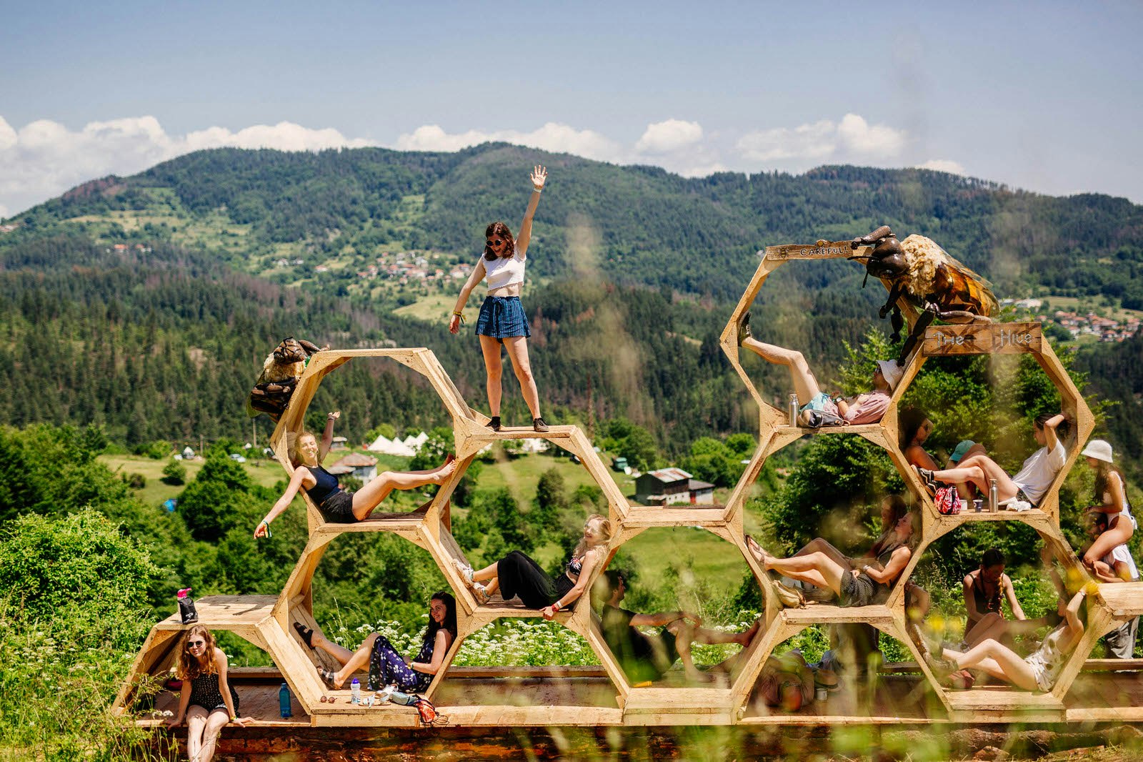 Europe music festival - people pose in and on a honeycomb sculpture in front of a mountain backdrop at Meadows in the Mountains, Bulgaria © Meadows in the Mountains / Aron Klein