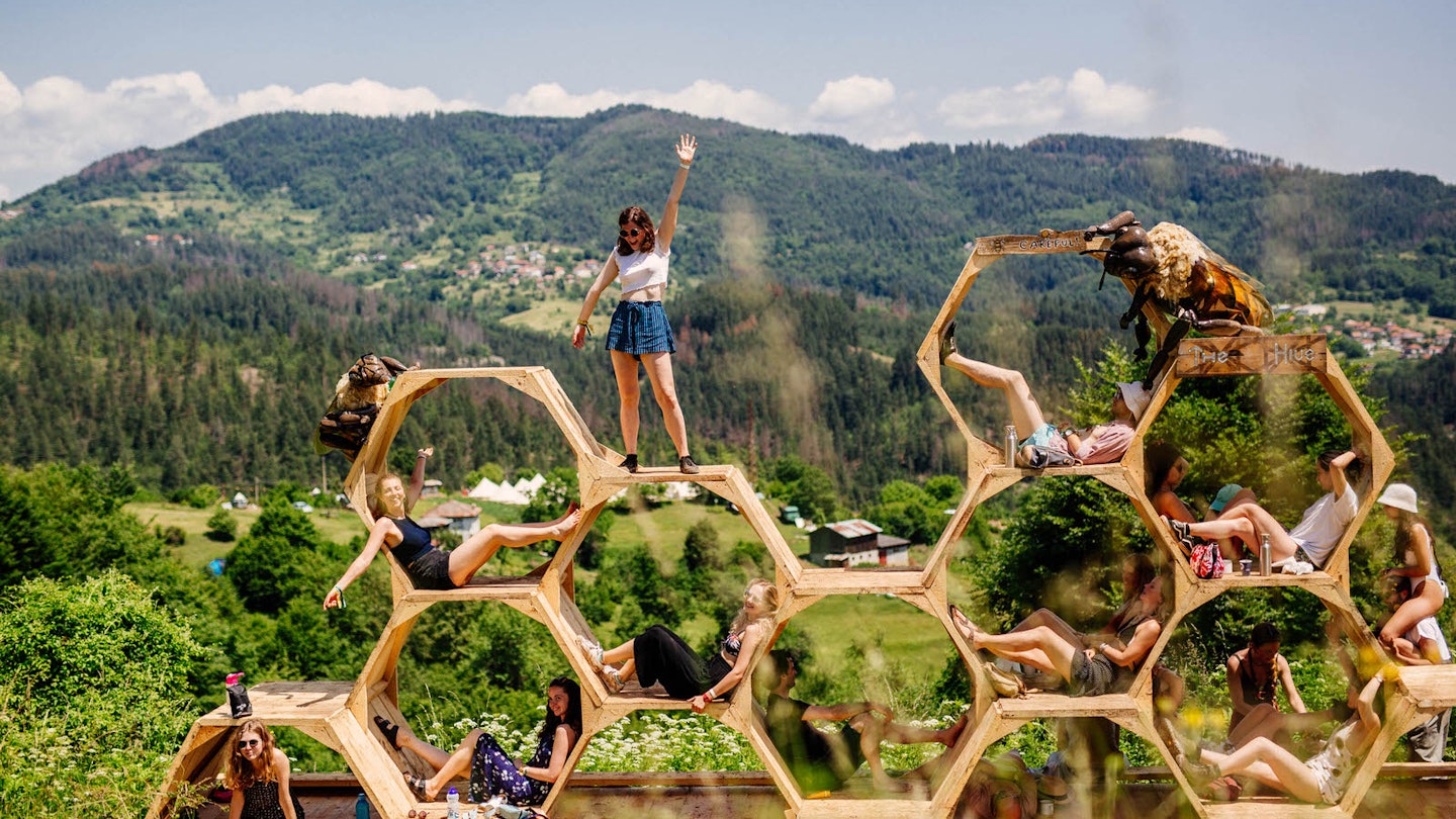 Europe music festival - people pose in and on a honeycomb sculpture in front of a mountain backdrop at Meadows in the Mountains, Bulgaria © Meadows in the Mountains / Aron Klein