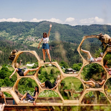 Europe music festival - people pose in and on a honeycomb sculpture in front of a mountain backdrop at Meadows in the Mountains, Bulgaria © Meadows in the Mountains / Aron Klein