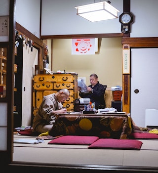Two monks hunch over paperwork at Eko-in