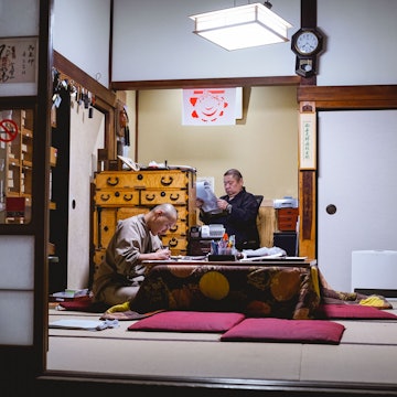 Two monks hunch over paperwork at Eko-in