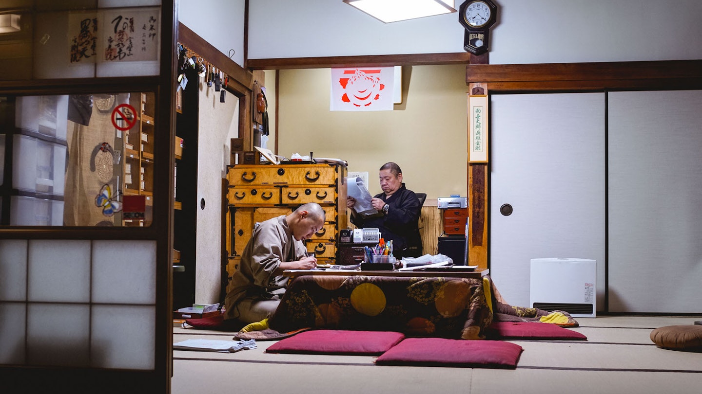 Two monks hunch over paperwork at Eko-in