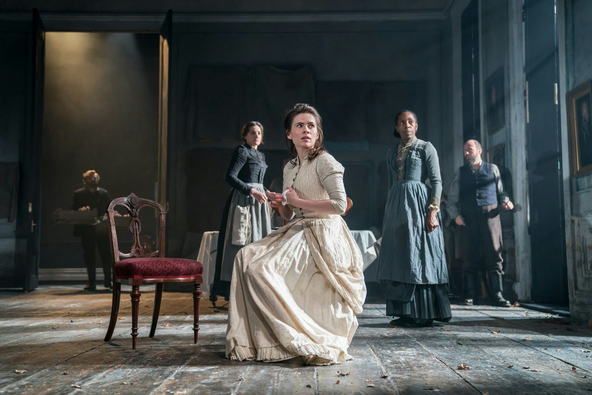 Celebrities West End Broadway- Hayley Atwell in Rosmersholm at the Duke of York's Theatre, London. Hayley perches on a chair in an old-fashioned white gown looking anxiously beyond the camera © Johan Persson