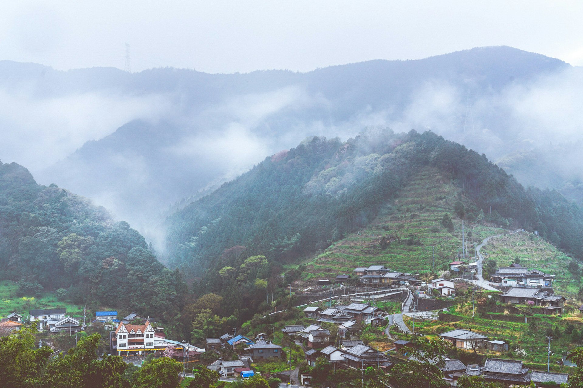 Kōya-san travel - Mountains reach up through mist, buildings clustering on the hills