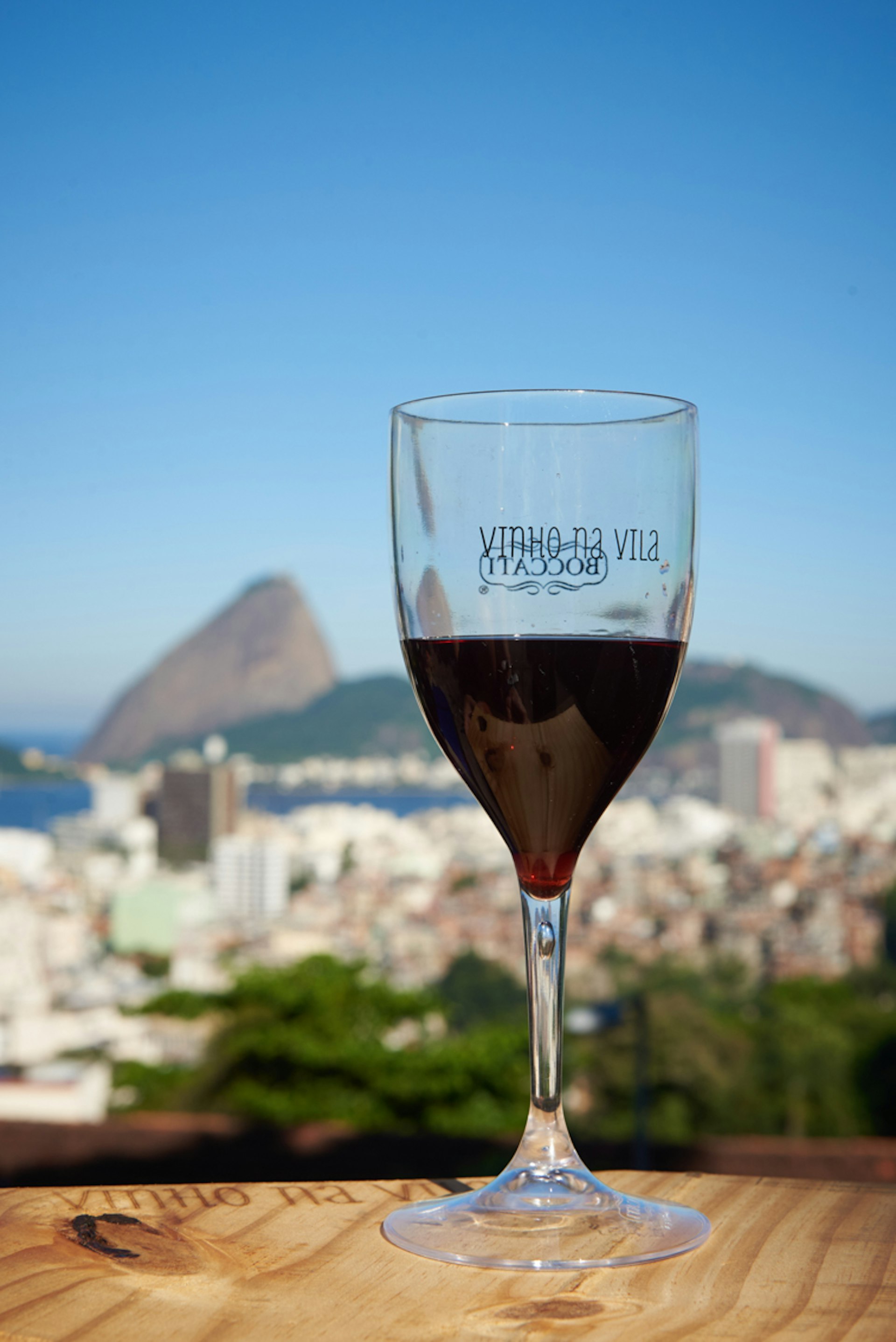 A wine glass filled with red wine sits on a wine barrel overlooking Rio de Janiero, Brazil