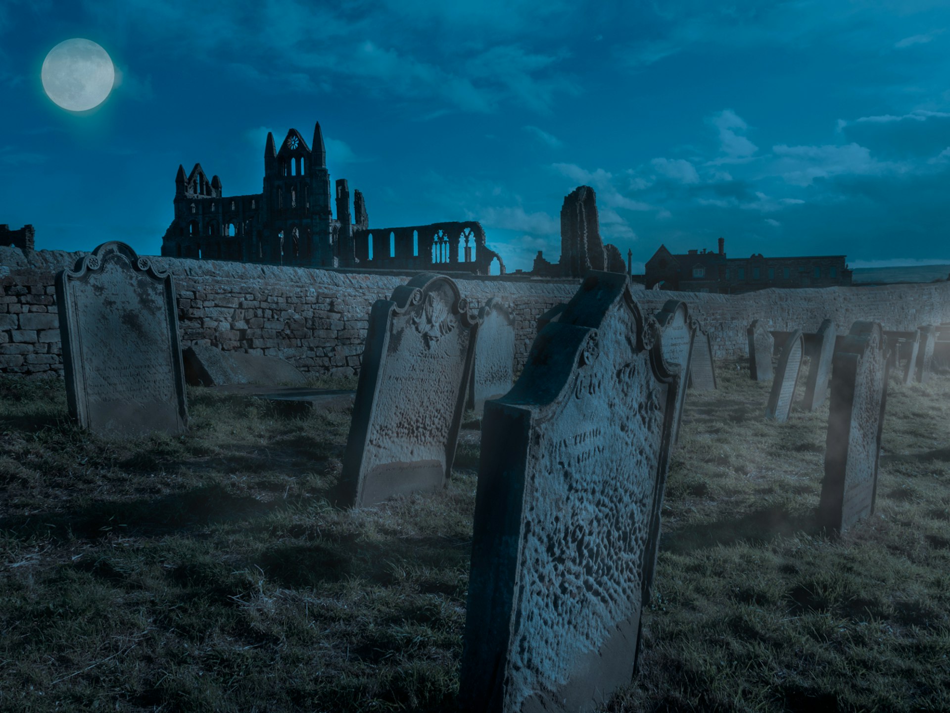 The ruins of Whitby Abbey and the graveyard under a full moon