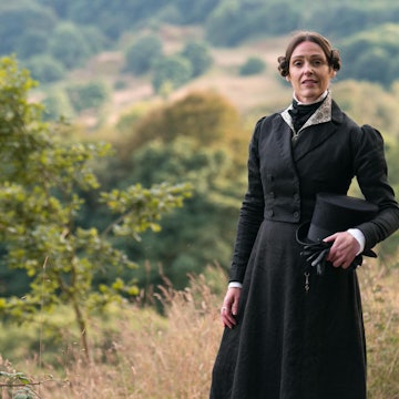 Actor Suranne Jones dressed as Anne Lister, stands holding her top hat with the Yorkshire landscape as a backdrop