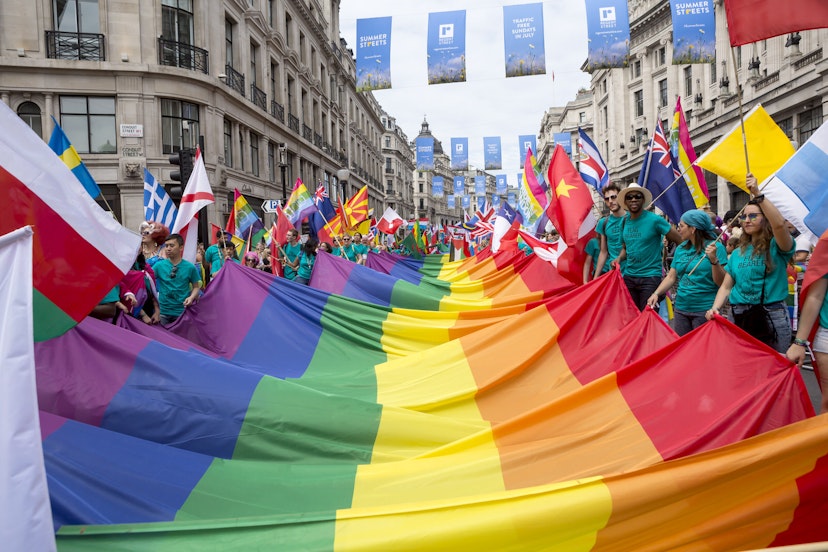 Pride in London parade participants carrying a huge rainbow flag along Regent Street