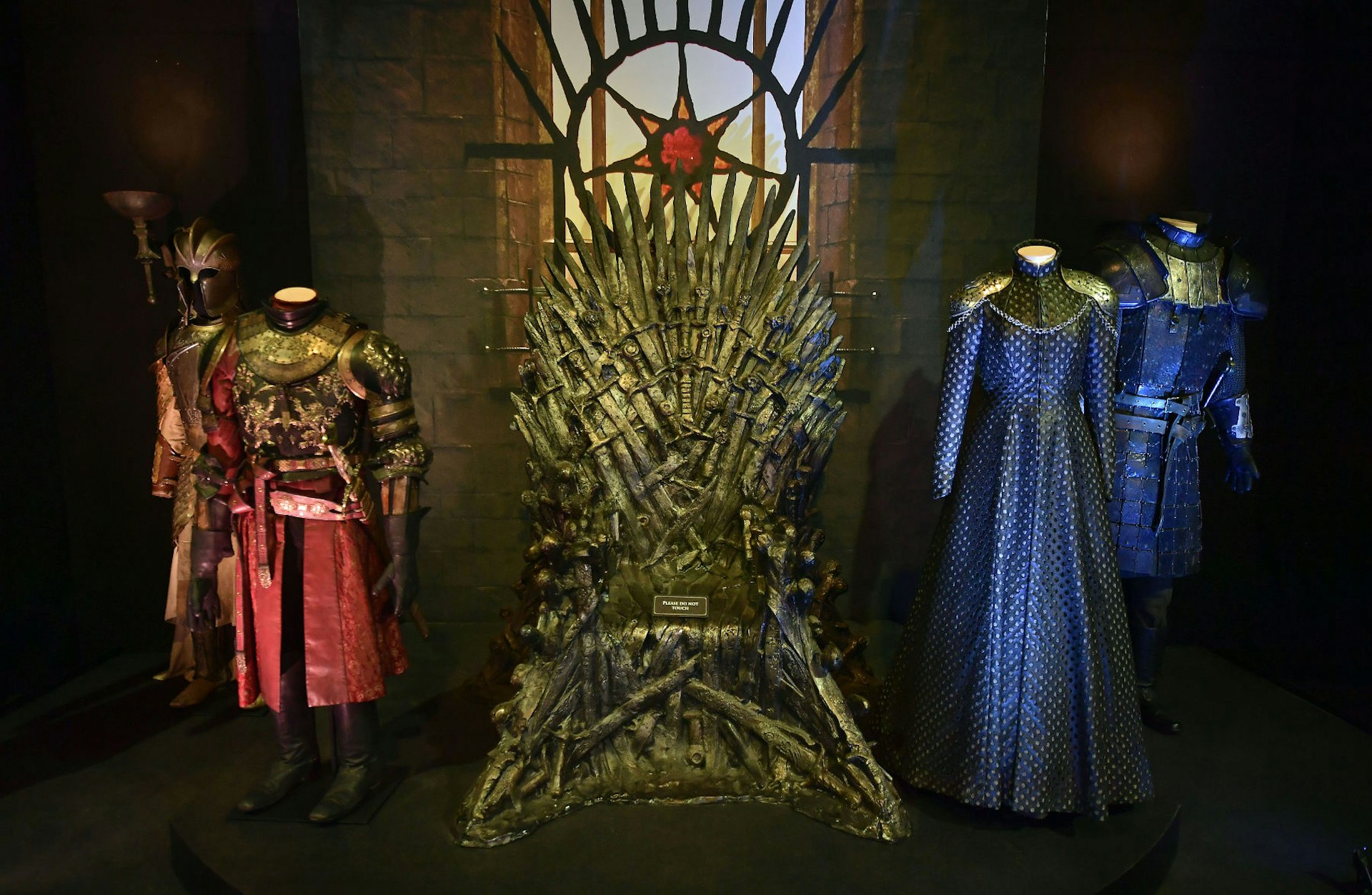 The Iron Throne with costumes from Game of Thrones on display on either side of it