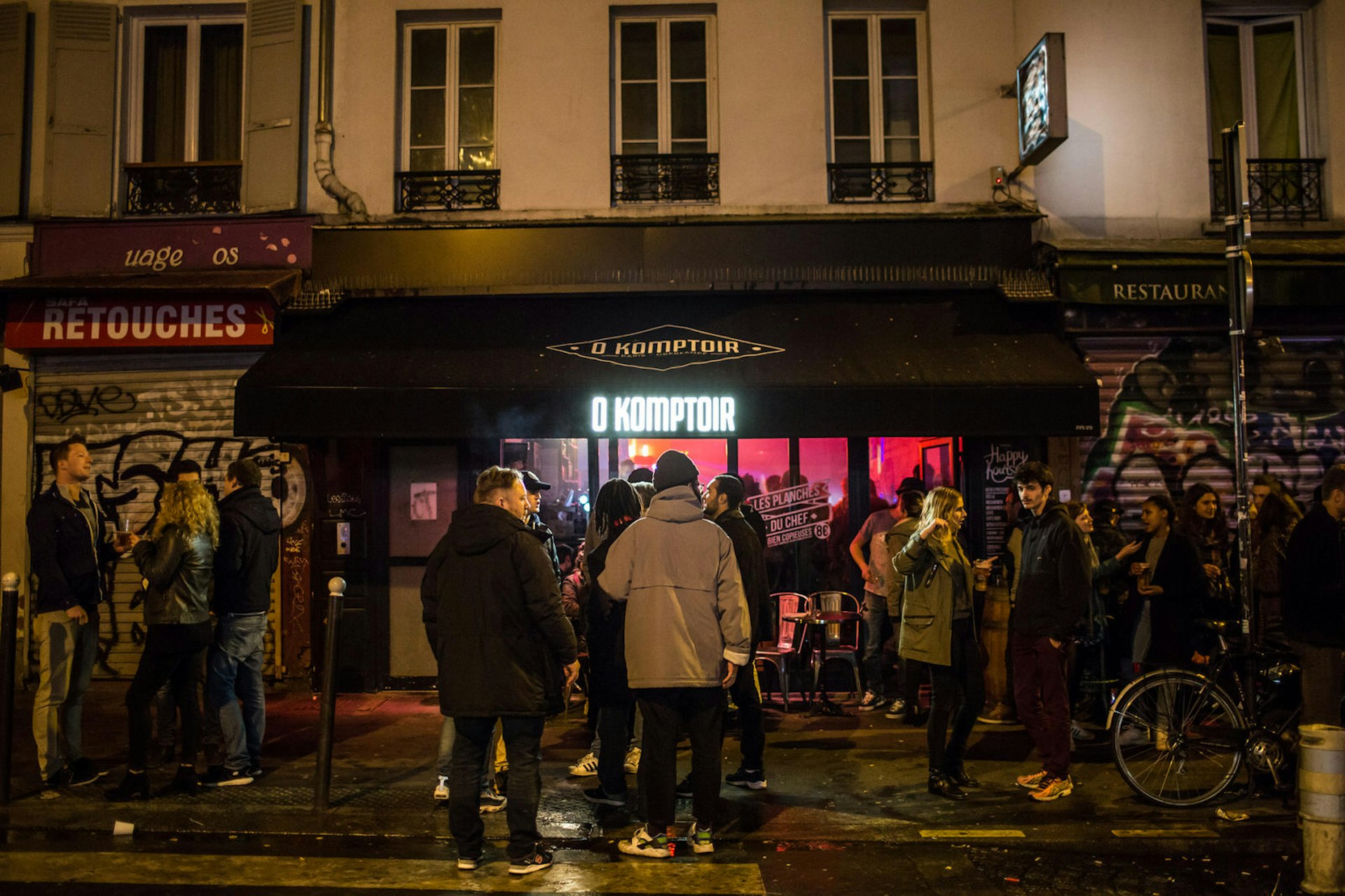 Groups of people outside O Komptoir, a bar on rue Oberkampf in the 11th Arrondissement, Paris